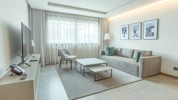 Un salon moderne comprenant un canapé, un fauteuil, une table basse et un téléviseur à écran plat.