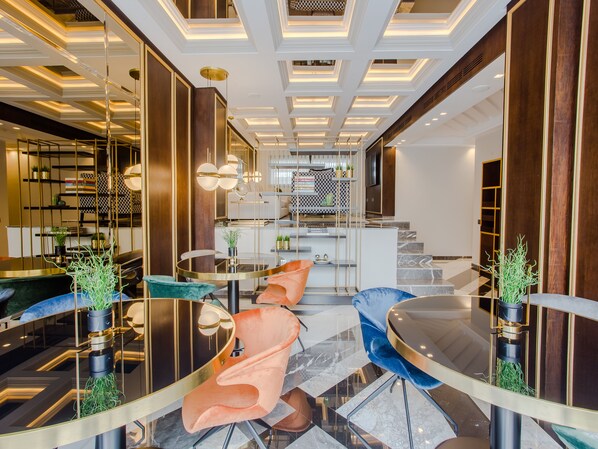 A modern interior with a central staircase, round tables, and plush seating. - Makass Appart Hotel (Rabat)