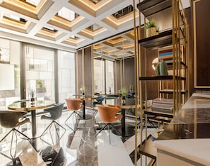 Un interior moderno con una mesa de vidrio, sillas de metal y una estantería de madera.