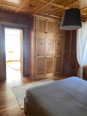 A room with a bed, wooden wardrobe, and a hanging light fixture. - 90sqm warm and cozy overlooking the square of Isolaccia.5 min from Bormio (Isolaccia)