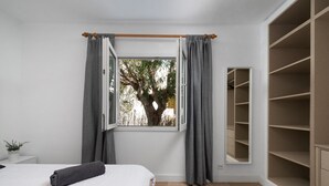 Un dormitorio con un ventanal grande, una cama, un armario y una planta en maceta.
