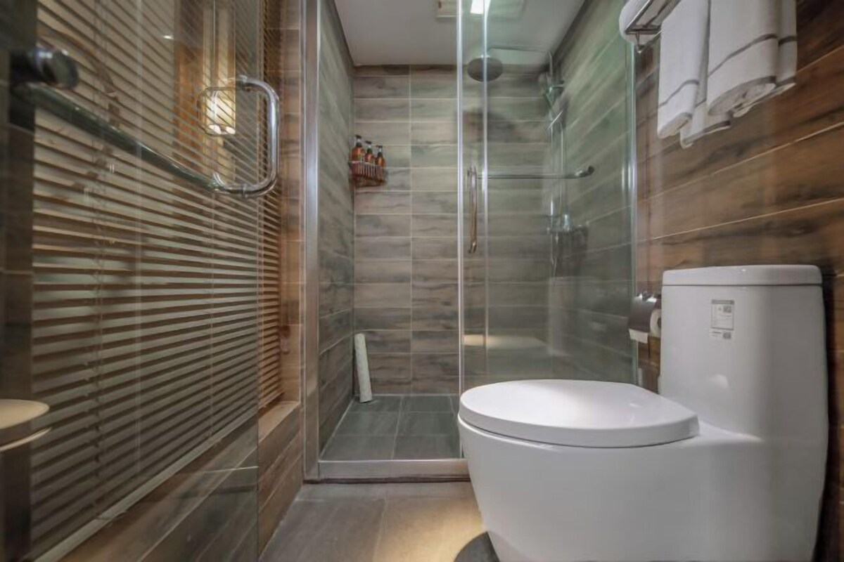 A modern bathroom with a glass shower enclosure, a white toilet, and a wooden wall.