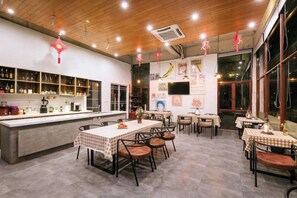 A restaurant interior with a bar area, dining tables, chairs, and a kitchen counter.