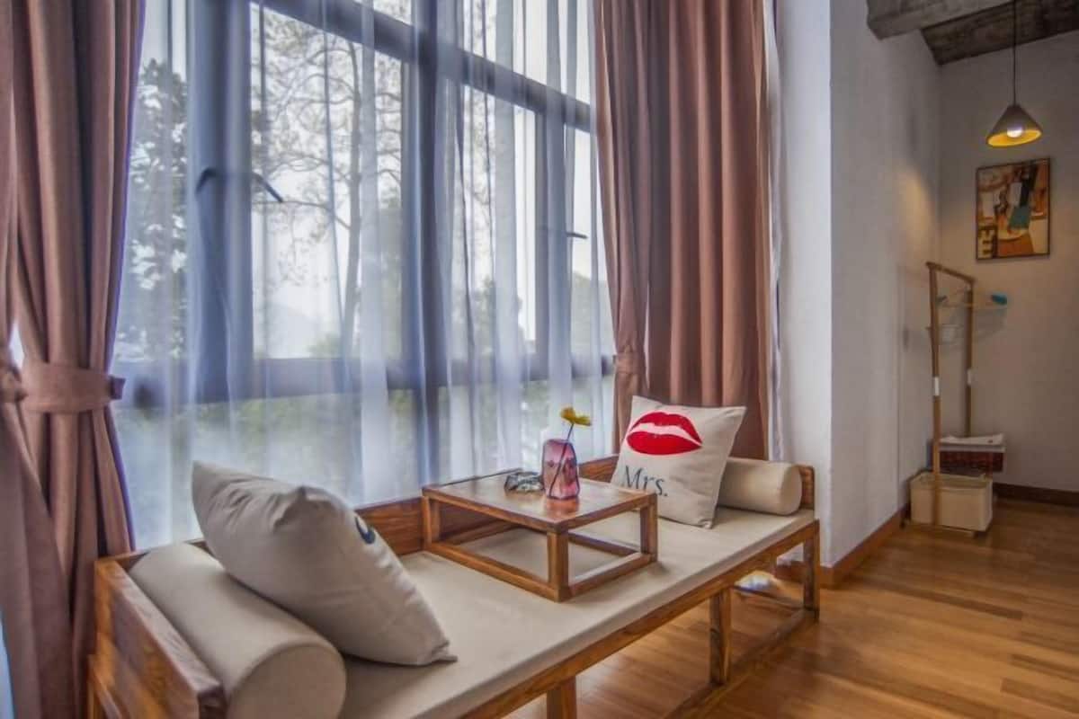 Un rincón acogedor con un banco acolchado, una mesita de madera y cortinas traslúcidas.