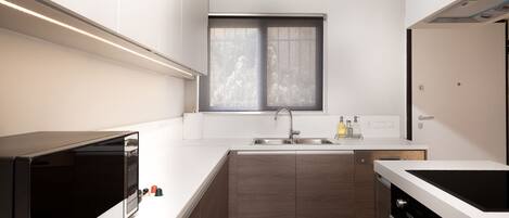 A modern kitchen with a built-in oven, a sink, and a window above it.
