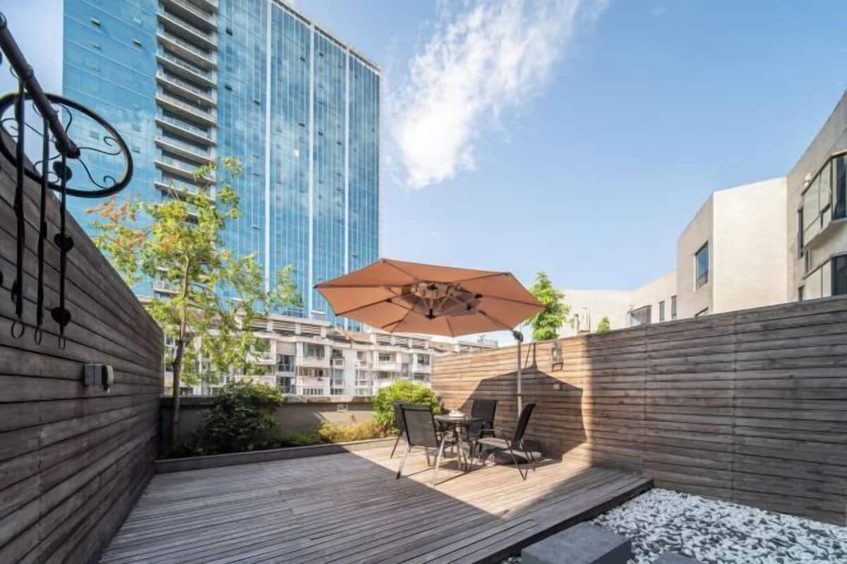 A rooftop patio with a wooden deck, outdoor furniture, and a large umbrella.