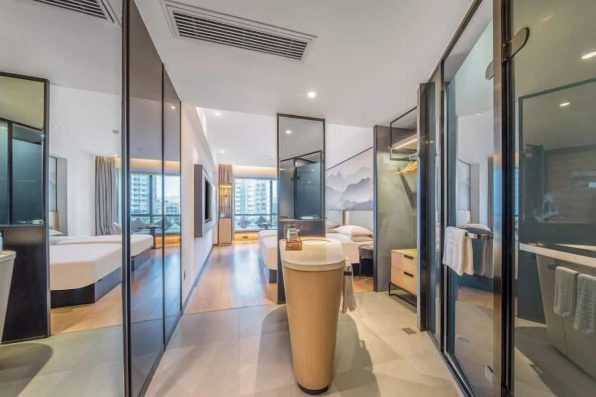 A modern hotel bathroom with a central sink, a shower area, and a glass partition.