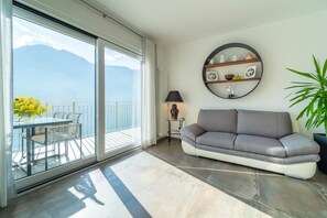 Un salon moderne comprenant un canapé, une table avec des chaises, une lampe et une étagère murale agrémentée d’objets décoratifs.