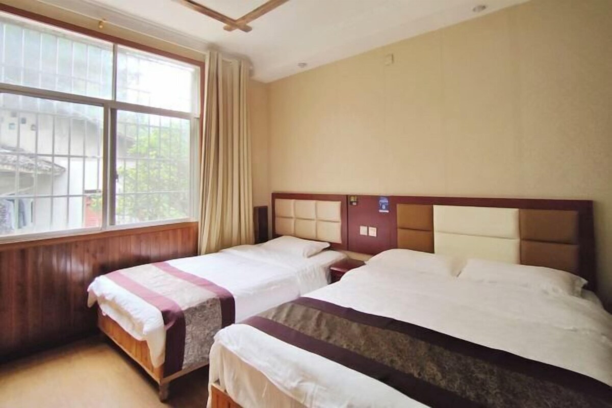 A hotel room with two beds, a window with curtains, and a wooden headboard.