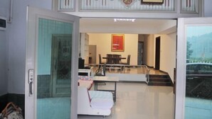 A hotel room with a glass door, a dining area with a table and chairs, and a bed with a white cover. - Guojia Courtyard Inn (Zhangjiajie)