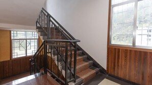 A staircase with a metal railing, wooden paneling on the walls, and a large window with a view. - Guojia Courtyard Inn (Zhangjiajie)