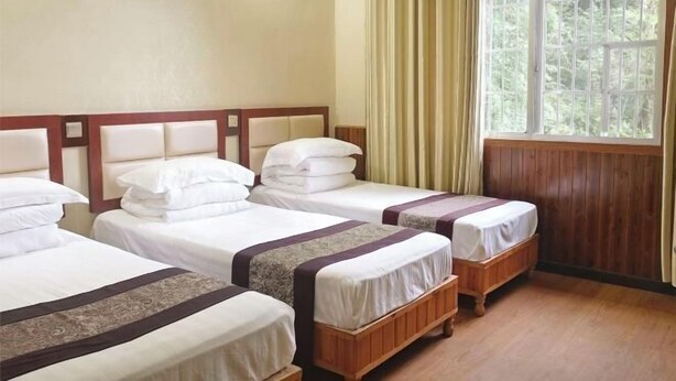 A hotel room with three single beds, wooden headboards, and a large window with curtains. - Guojia Courtyard Inn (Zhangjiajie)