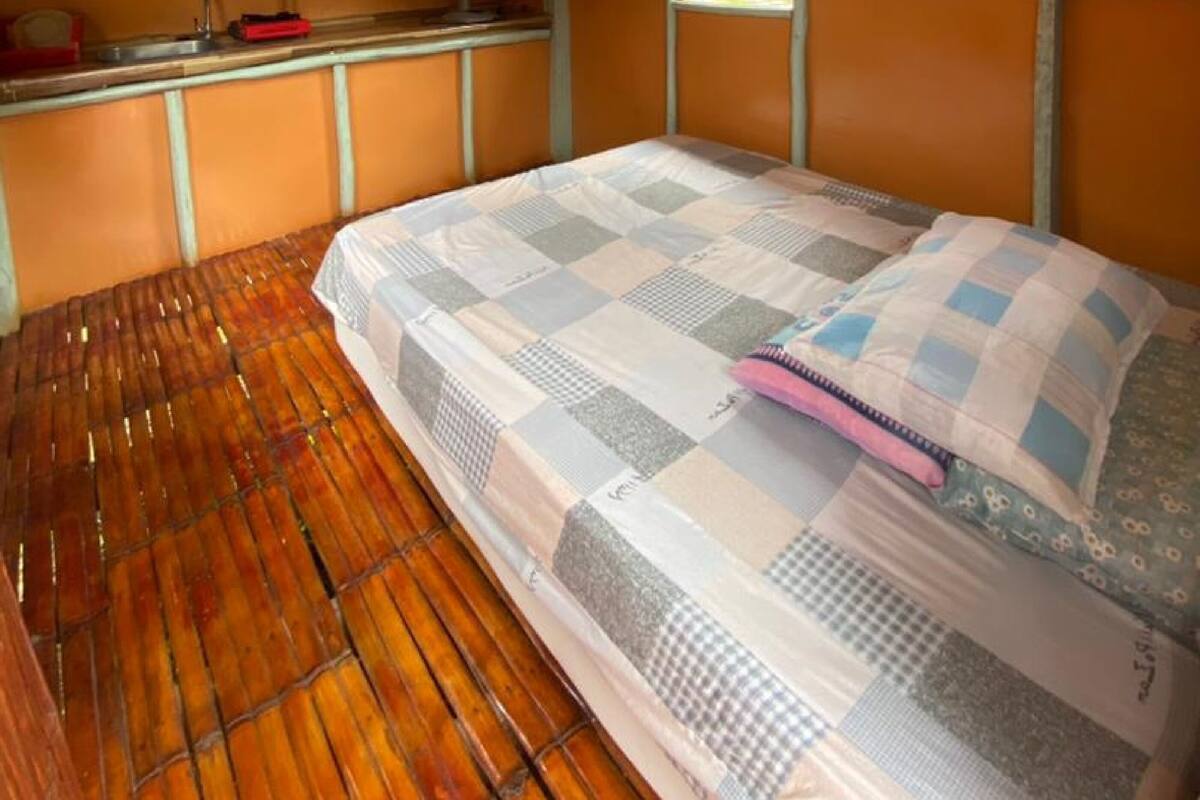 A room with a bed, a window, a fan, and a sink.
