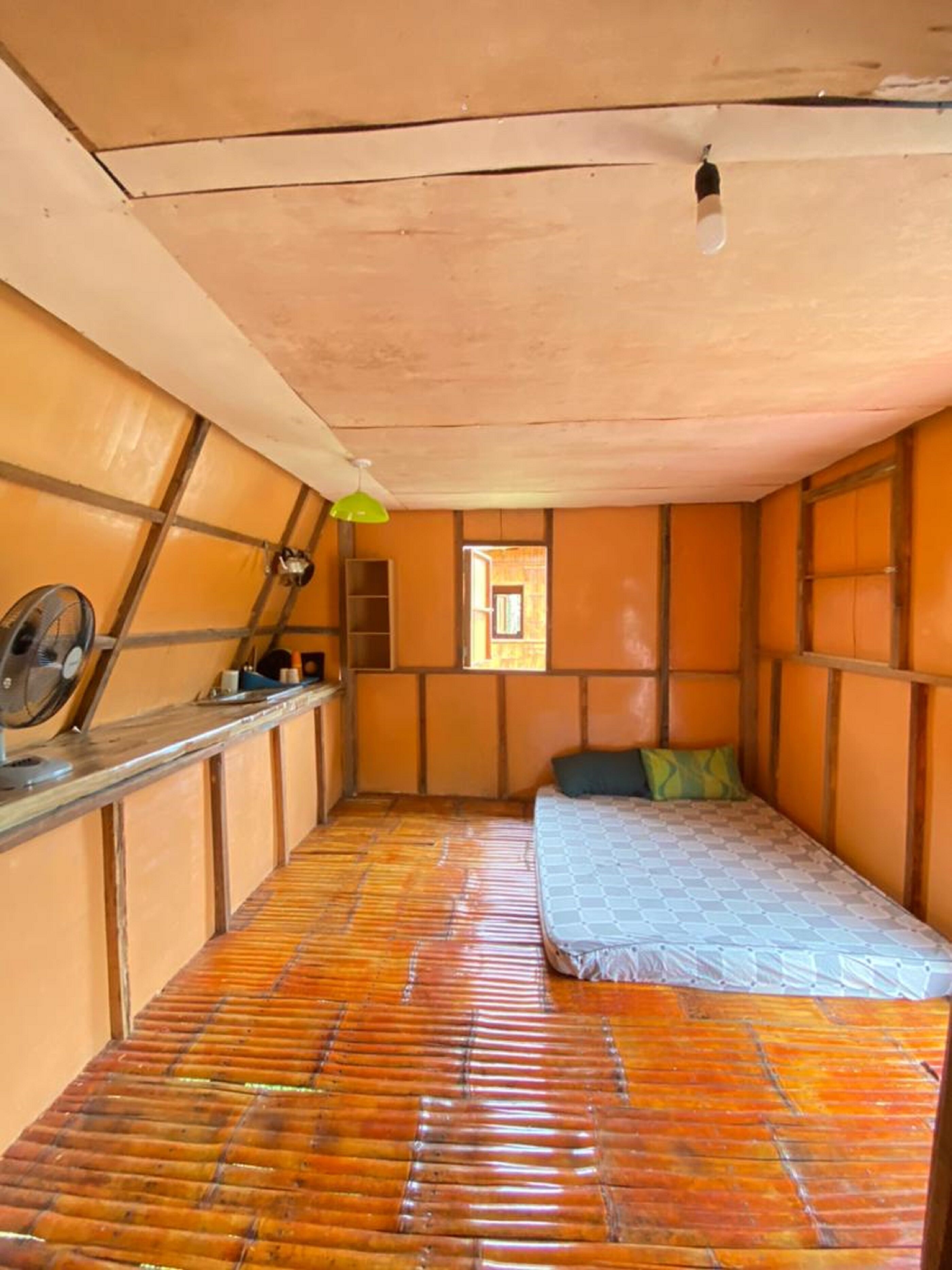 Una stanza con un letto, un tavolino, una lampada verde e una finestra.