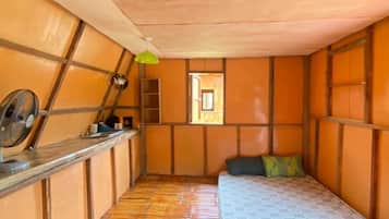 Una stanza con un letto, un tavolino, una lampada verde e una finestra.