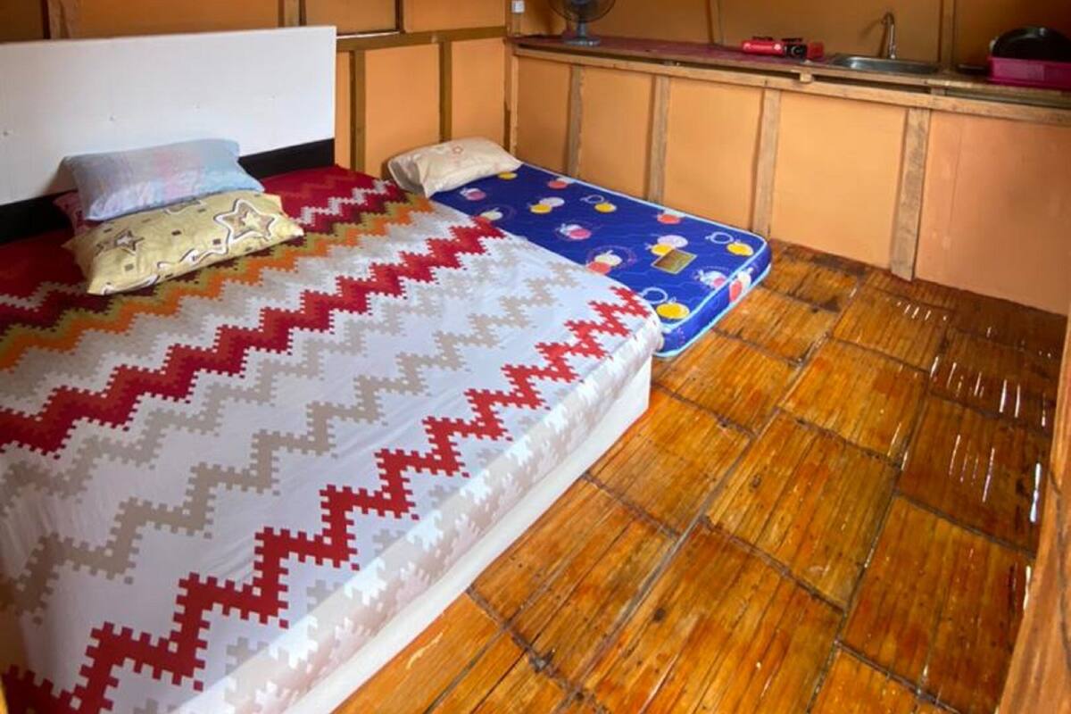 A small, compact room with a bed, a small table, and a kitchenette area.