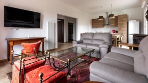 A modern living room with a sofa, a glass coffee table, and a red patterned bed. - Casa con Giardino a Borgo Panigale (Bologna)