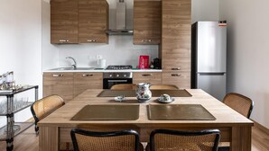 A modern kitchen with wooden cabinets, a stainless steel refrigerator, and a dining area with a table and chairs. - Casa con Giardino a Borgo Panigale (Bologna)