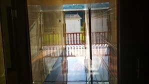 A corridor with glass walls, leading to an outdoor area with a white fence and a building in the background. - Langshan Patriotic Farm (Xinning)