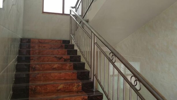 A staircase with marble steps and metal railings, leading to a landing with a window. - Langshan Patriotic Farm (Xinning)