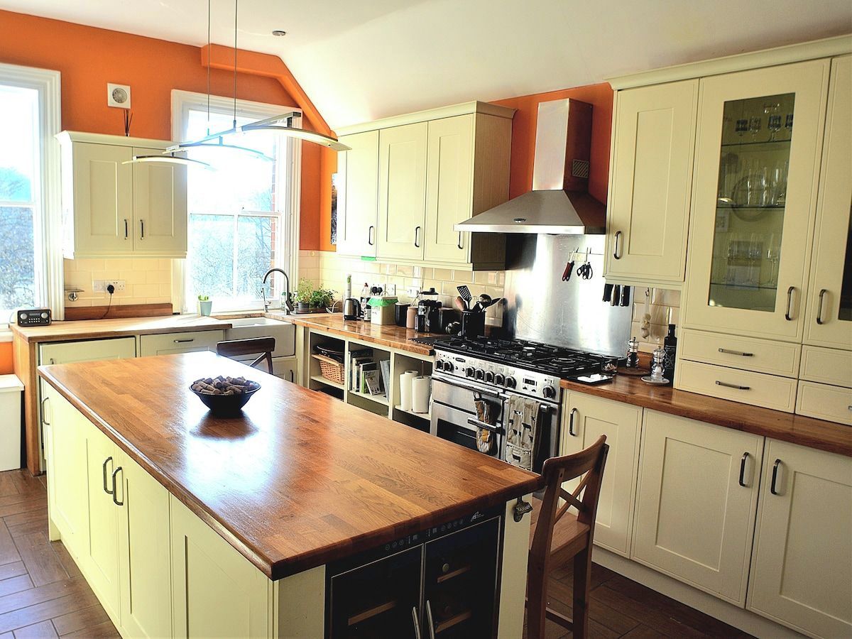 A kitchen with a central island, white cabinets, a stove, and a range hood.