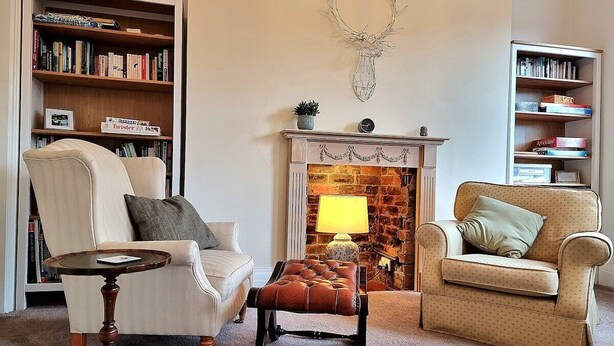 Uma sala de estar aconchegante com lareira, estante de livros e dois poltronas.