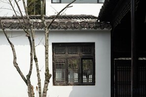 A traditional building with a tiled roof, a window with a grid pattern, and a tree in the foreground. - Huzhou Biocountry Resort (Changxing)