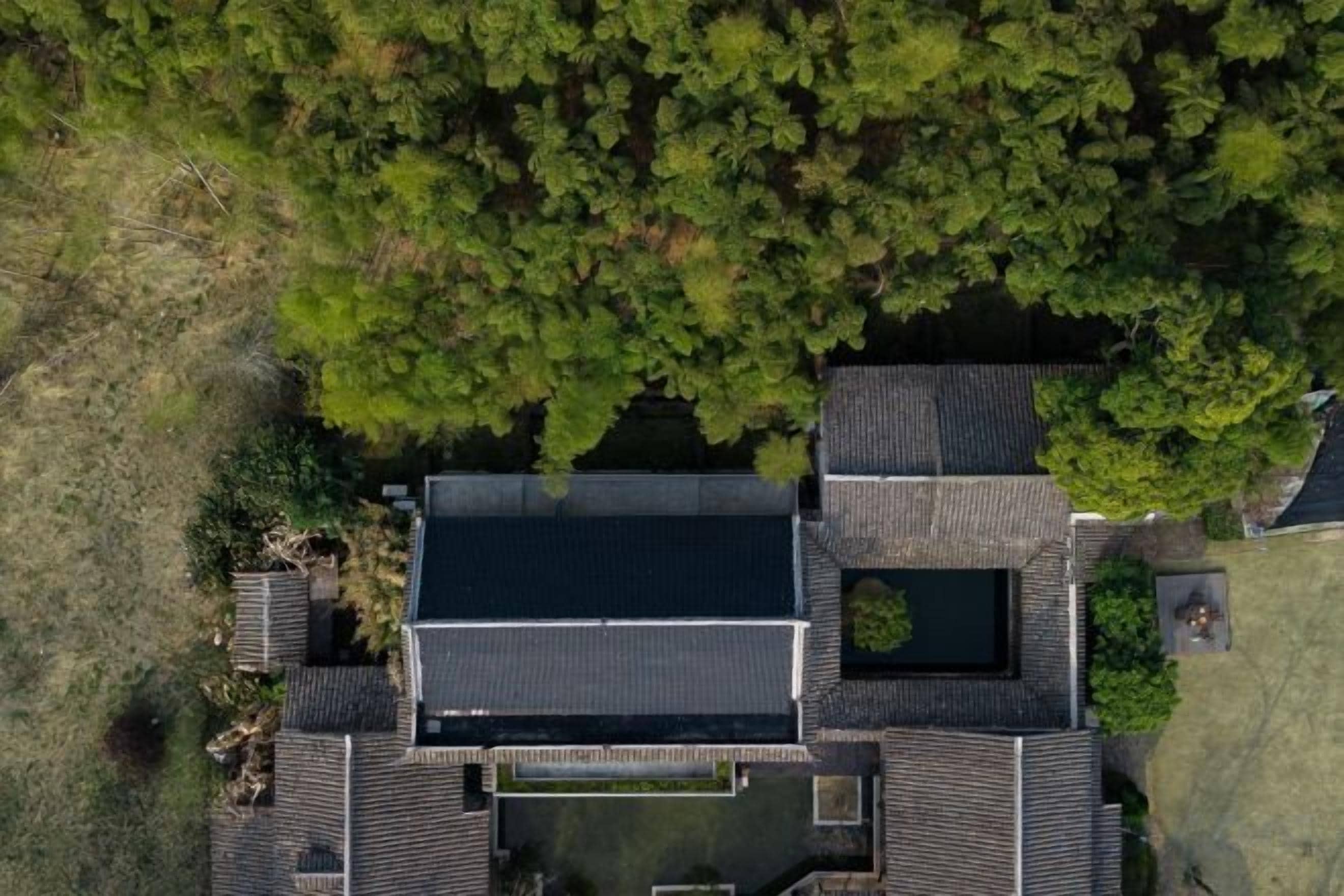 Luchtbeeld van een pand met meerdere gebouwen, een centrale binnenplaats en omliggend groen.