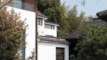 Un edificio tradicional con fachada blanca y tejado de tejas, rodeado de árboles.