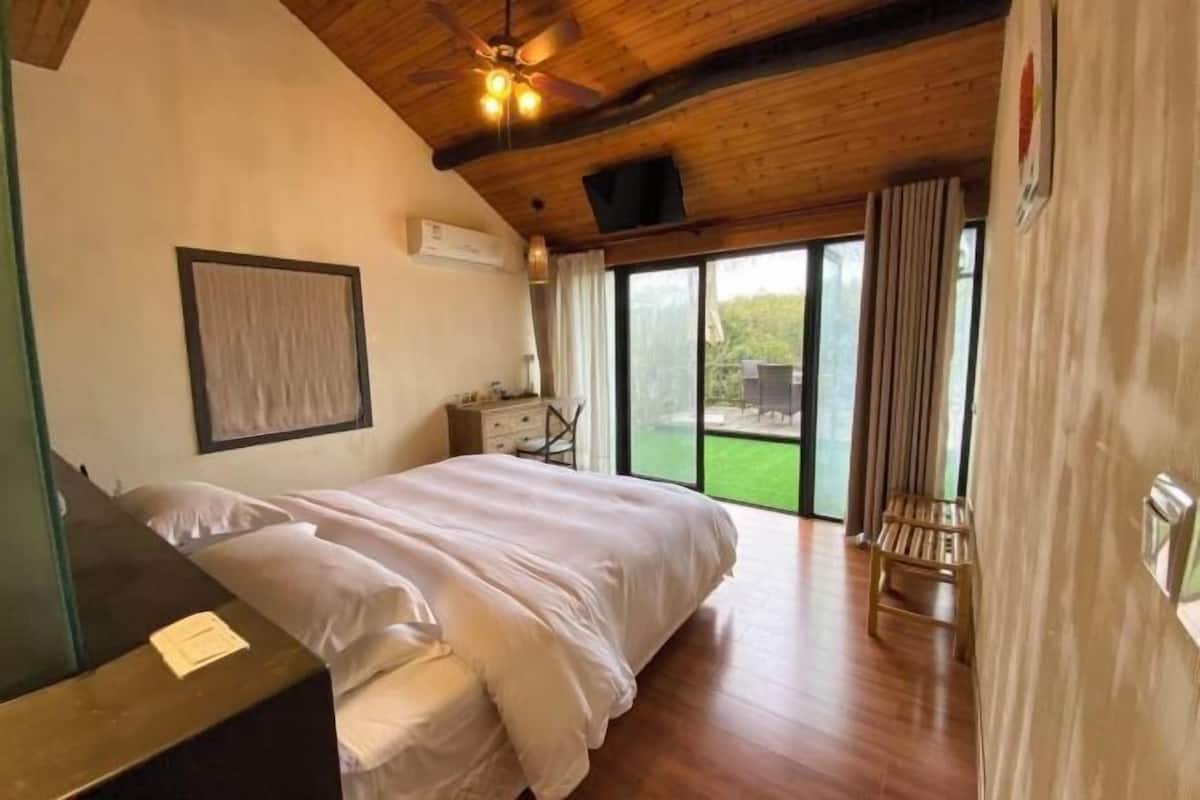 Une chambre à coucher avec un lit, un bureau, une chaise et une vue sur l’extérieur.