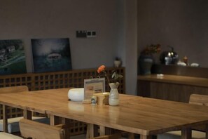 Una mesa de comedor de madera con un florero, un cuadro enmarcado y un adorno decorativo.