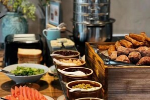 Ein Buffet mit einer Auswahl an Speisen, darunter Obst, Nüsse und Gebäck.