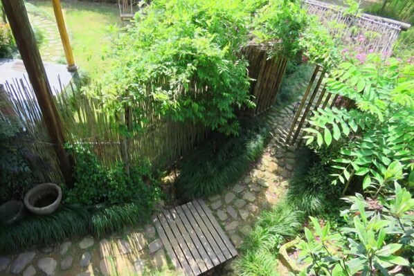 A garden with a stone pathway, wooden bench, and various green plants. - Huzhou Biocountry Resort (Changxing)