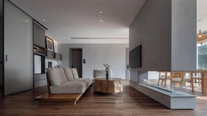 A modern living room with a sofa, coffee table, and a TV mounted on the wall. - Huzhou Biocountry Resort (Changxing)