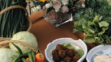 Una mesa con comida, un tazón de albóndigas y un florero con flores.