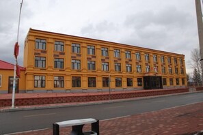 Un edificio amarillo con fachada simétrica, varias ventanas y tejado rojo.