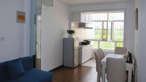 A compact living space with a kitchenette, a dining area, and a sofa. - Tahe Eighteen Post Residence (Tahe)