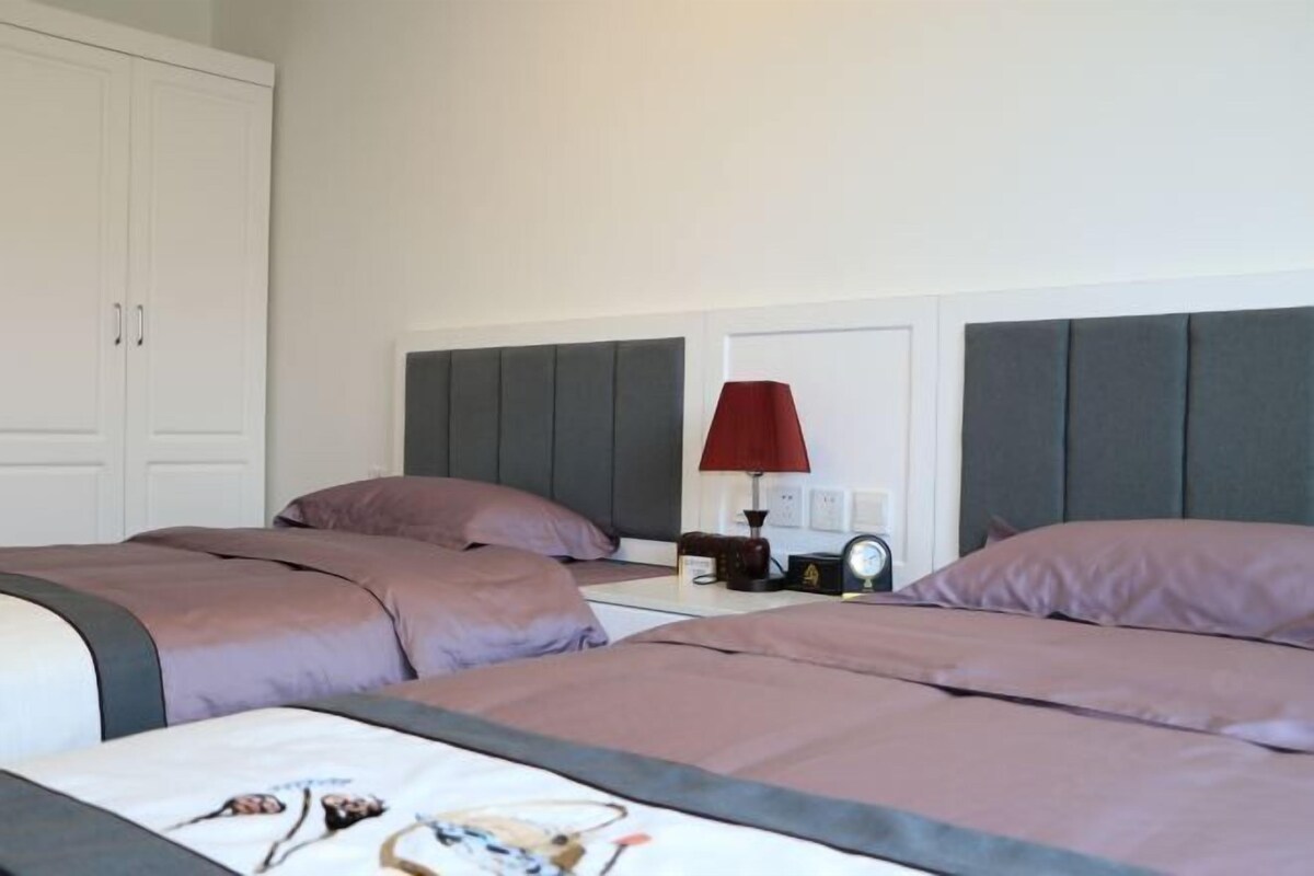 Una habitación de hotel con dos camas, una mesita de noche con lámpara y un armario.