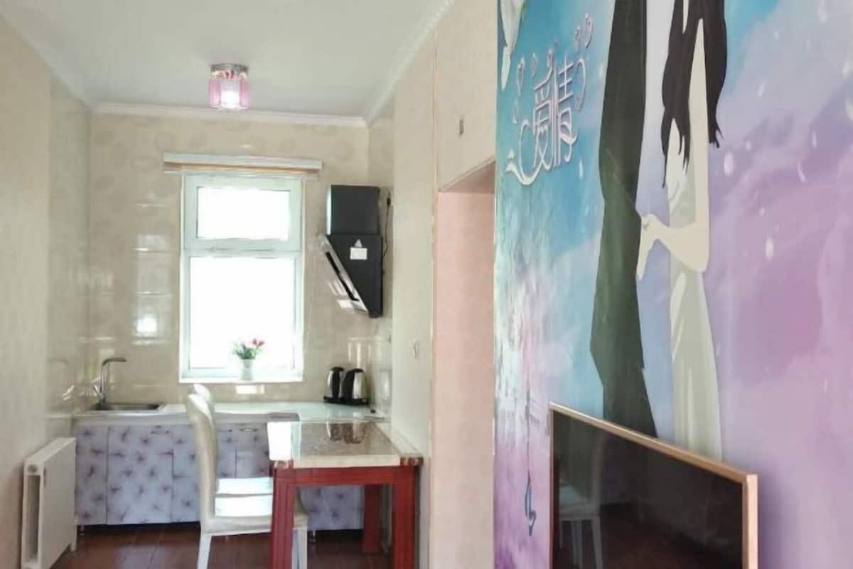 A small kitchen with a window, a refrigerator, a sink, and a chair.