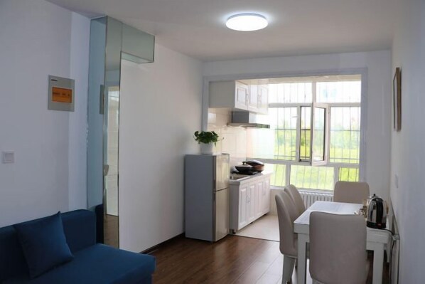 Un espacio habitable compacto con kitchenette, comedor y sofá.