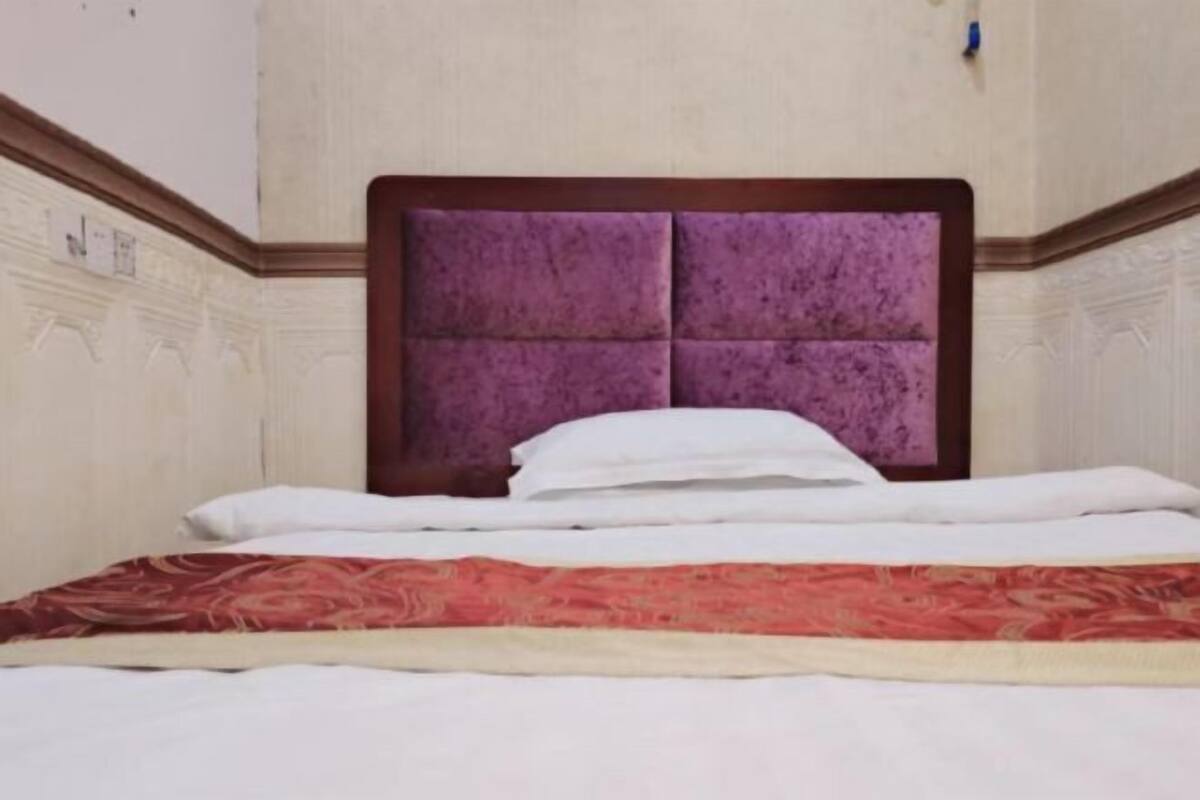 A bed with a wooden headboard and a red patterned bedspread.