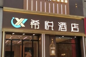 A hotel entrance with a sign that reads "Xingfu Hotel." - Xiyue Theme Inn (Xianyang)