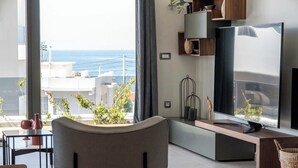 A modern living room with a view of the sea, a flat-screen TV, and a minimalist design. - Lusol Seafront Villas (Chania)
