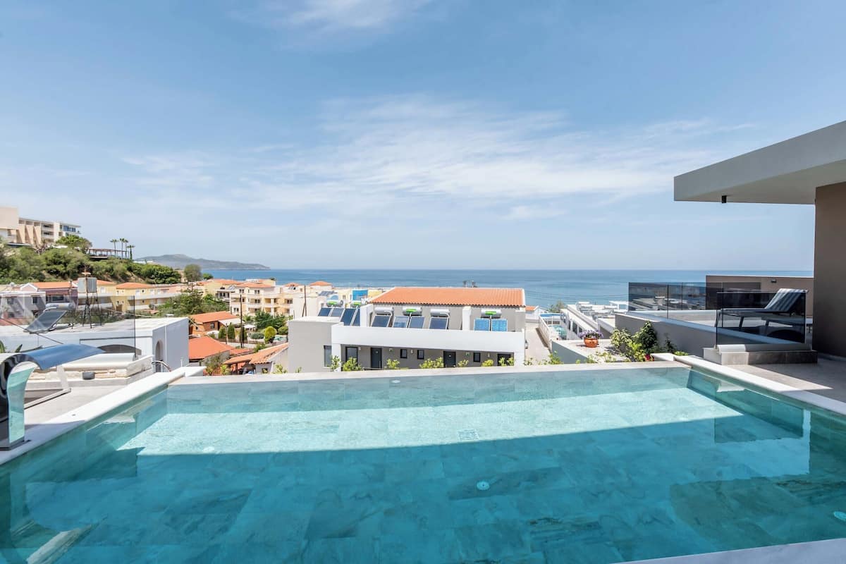 A rooftop infinity pool with a view of the sea and surrounding buildings.