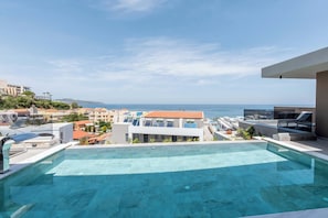 A rooftop infinity pool with a view of the sea and surrounding buildings.