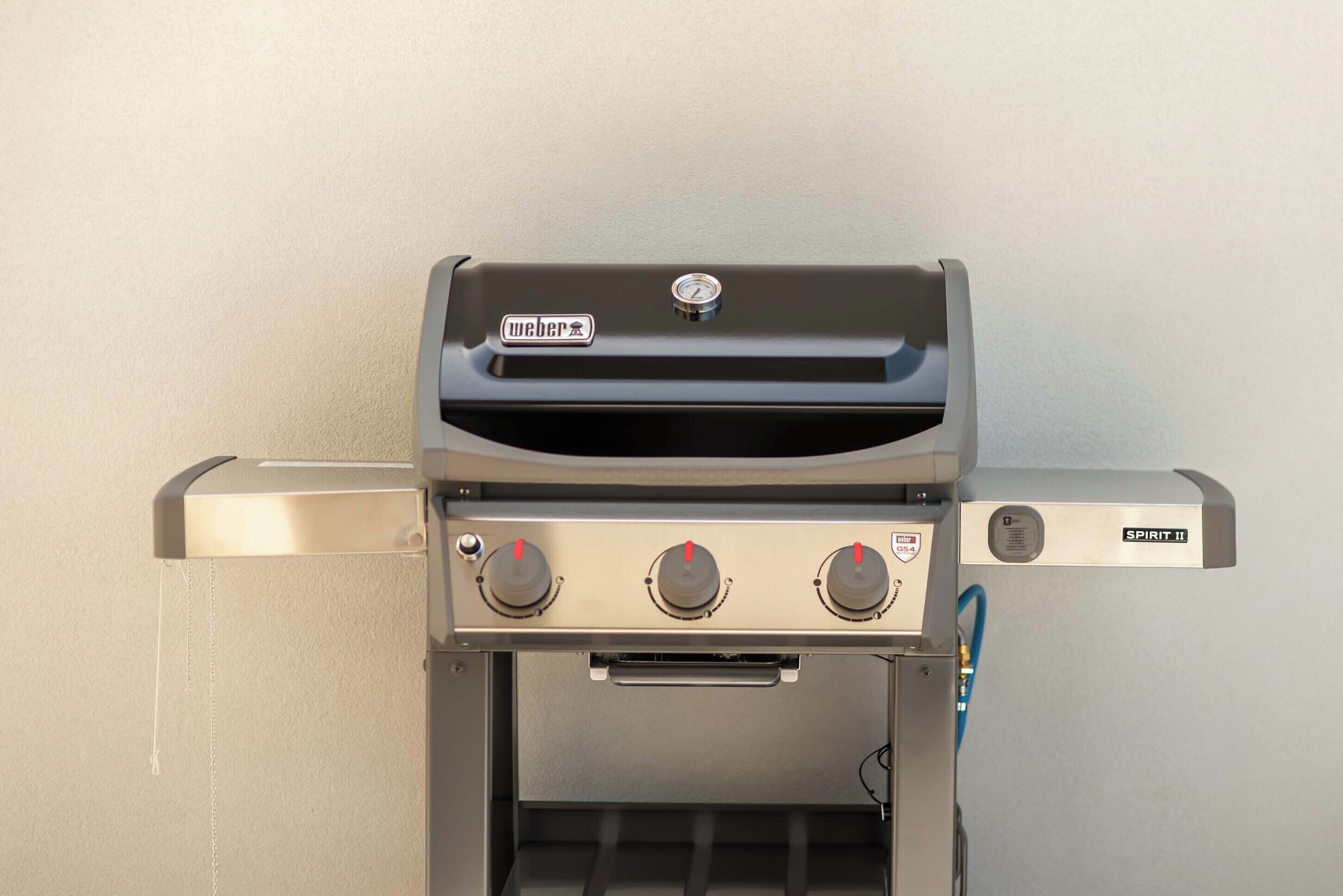 Una parrilla Weber Spirit II con tres perillas de control y una pantalla digital.