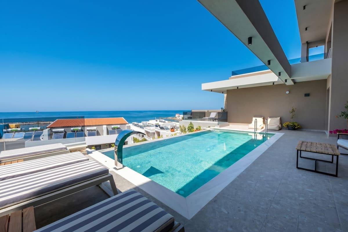 A rooftop pool with lounge chairs, a clear view of the ocean, and a modern architectural design.