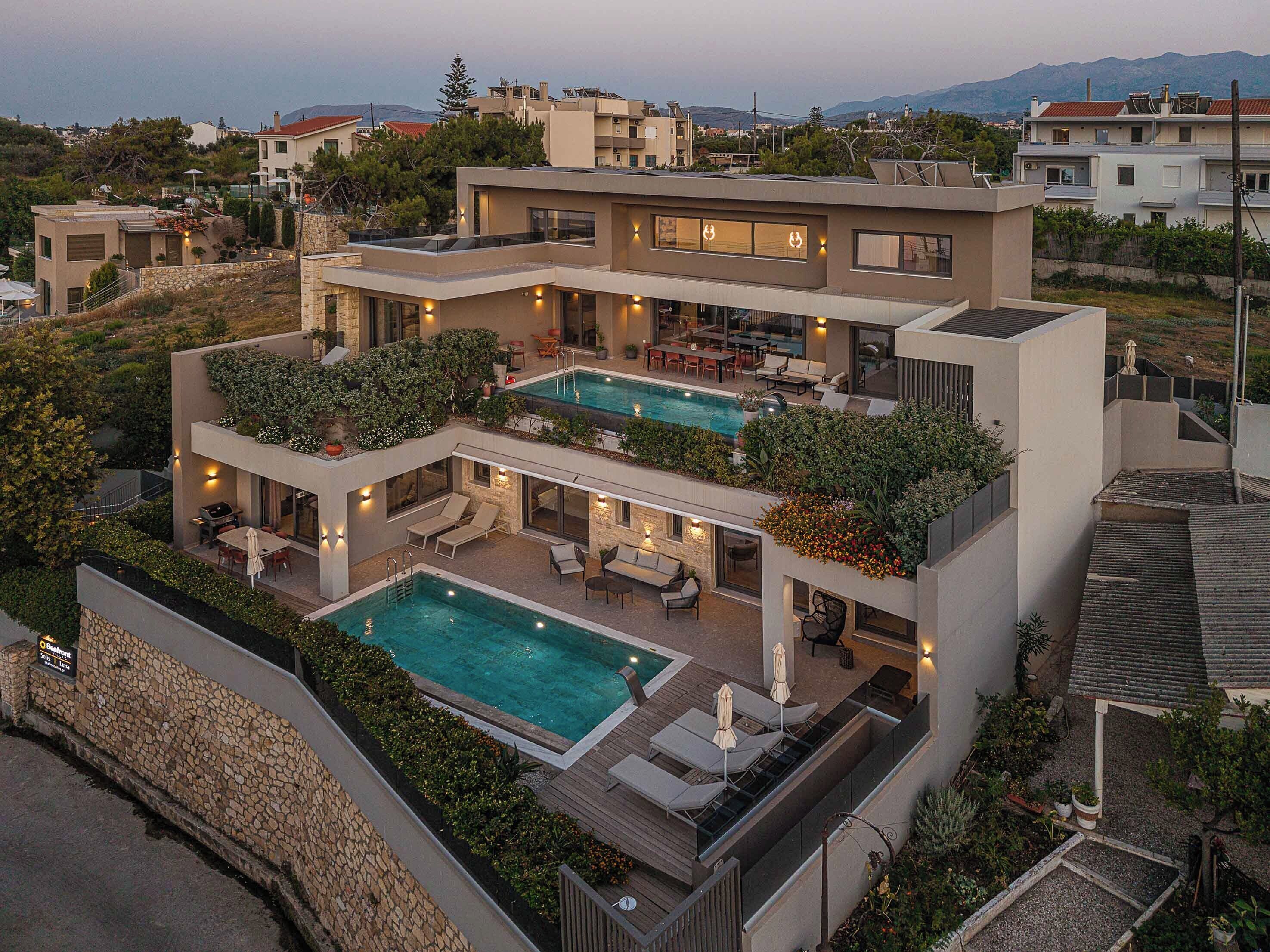 A modern multi-story house with a rooftop pool and outdoor seating areas.