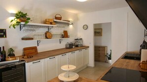 Une cuisine avec des meubles blancs, un plan de travail en bois, un évier et un coin repas comprenant une table et des chaises.