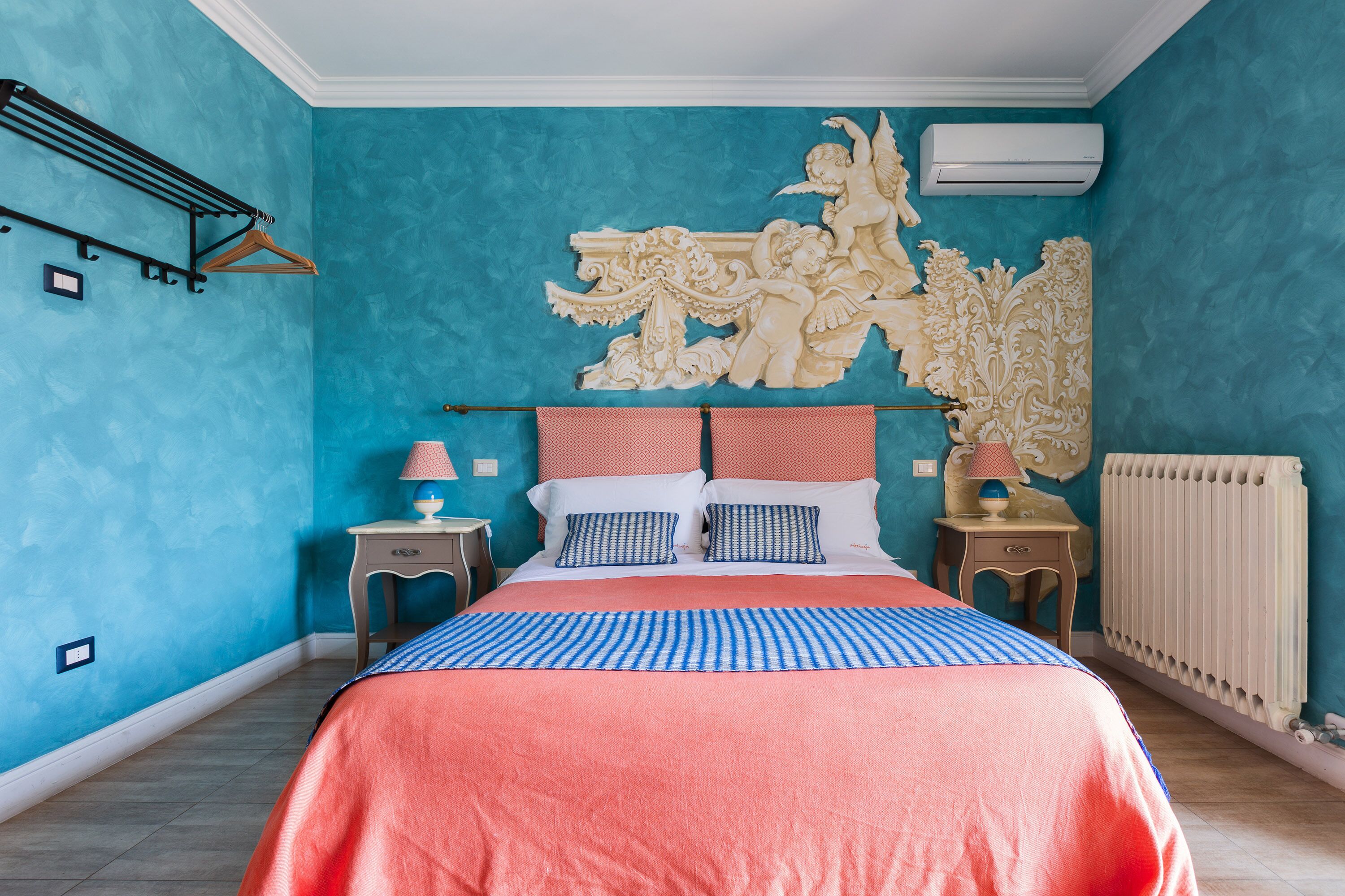 Ein Schlafzimmer mit einem großen Bett, einer dekorativen WandSchnitzerei, einem Heizkörper und einem Handtuchhalter.